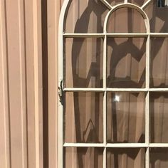 an old white window with glass panes on the side of a building in front of it