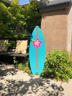 a blue surfboard sitting on the side of a building next to a park bench