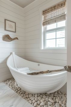 a white bath tub sitting on top of a pebble floor next to a window