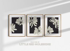 three black and white flowers are hanging on the wall