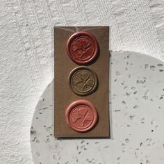 three waxed buttons sitting on top of a piece of paper