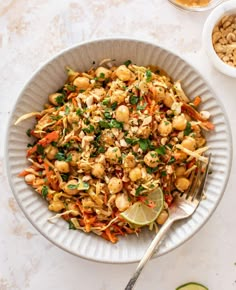 a white bowl filled with food next to two bowls of nuts and limes on the side