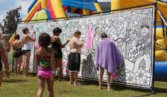 some kids are standing in front of a wall with graffiti on it and one kid is wearing a purple towel