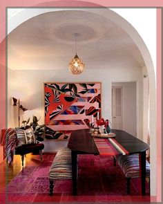 a living room filled with furniture and a large painting on the wall above an arched doorway