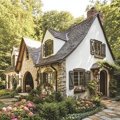 a white house surrounded by flowers and greenery