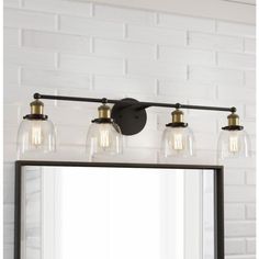 a bathroom vanity light with three clear glass jars on the top and one black metal frame