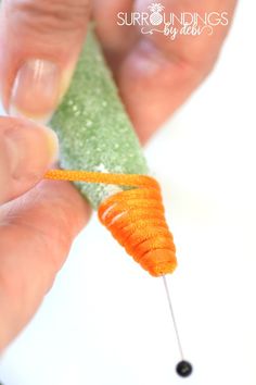 a person is holding a carrot on a stick with some sort of thread attached to it