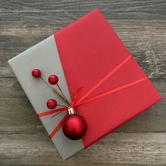 a red christmas ornament sitting on top of a present box with ribbon around it