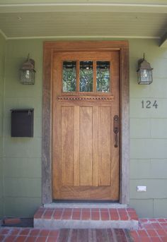 the front door to a home with brick steps and lanterns on either side of it