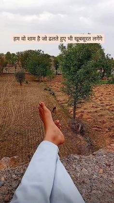 someone is laying down on the ground with their feet up in front of an open field