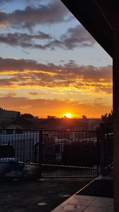 the sun is setting over some buildings and cars