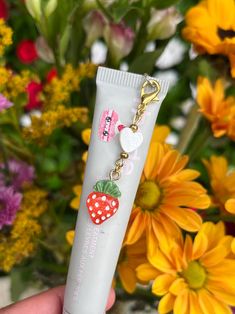 the lip bale is being held up by a person with flowers in the background