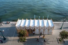 an aerial view of people walking on the sidewalk next to a large structure with white fabric covering it