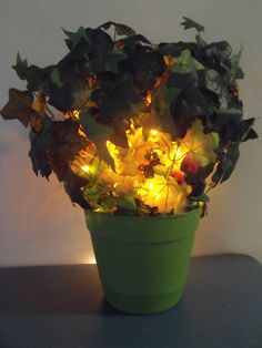 a green pot filled with lots of flowers on top of a table