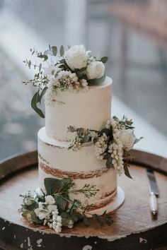 a three tiered cake with flowers and greenery on top