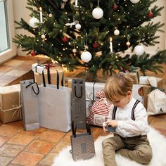 a little boy sitting on the floor next to christmas presents