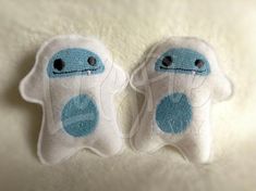 two blue and white stuffed animals sitting on top of a bed next to each other