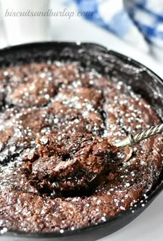 a close up of a cake in a pan on a plate with powdered sugar