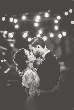 a bride and groom kissing on the dance floor at their wedding reception in black and white