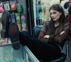 a woman is sitting on a chair in front of a store window with her legs crossed