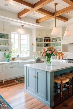 a kitchen with white cabinets and blue island