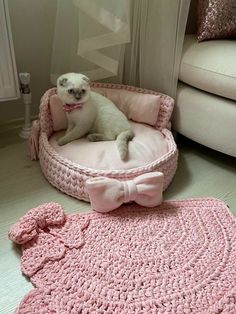 a small white dog sitting in a pink crocheted bed with a bow tie