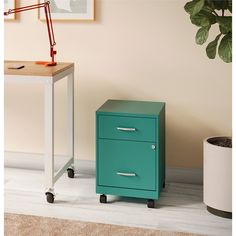 a green filing cabinet sitting next to a plant on top of a wooden table in front of a white wall