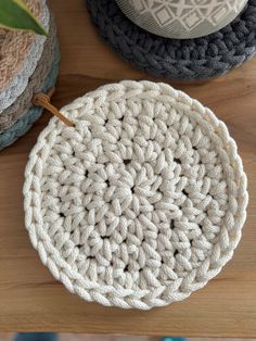 three crocheted coasters sitting on top of a wooden table