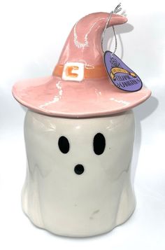 a white ceramic pot with a pink hat on it's head and a tag attached to the top