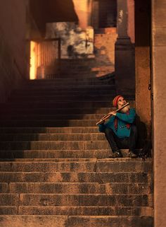 a man sitting on some steps with a pipe in his mouth and looking up at the sky