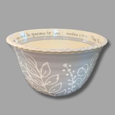 a bowl with white designs and words on the rim, sitting against a gray background