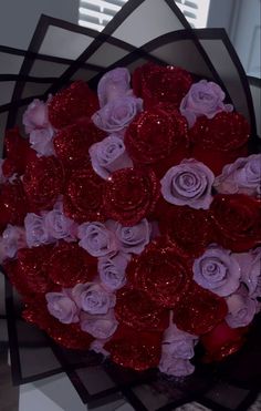 a bouquet of red and purple roses in a heart shaped paper box with sequins