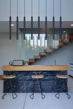 the modern kitchen has black marble counter tops and wooden stools, along with hanging lights that hang from the ceiling