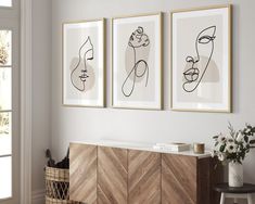 three framed art pieces hang on the wall above a sideboard in a living room