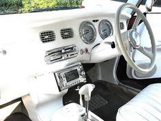 the interior of an old car with white leather seats and dash board, steering wheel and dashboard