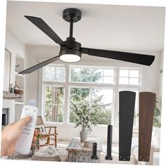 a person is holding a remote control in front of a ceiling fan with three blades