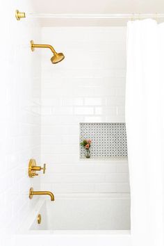 a white bathroom with gold fixtures and tile on the shower wall, along with a bathtub