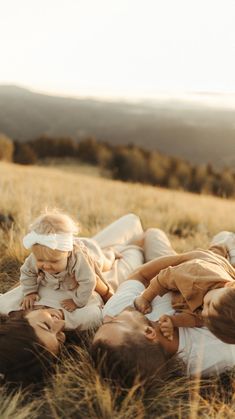 a woman and two children laying in the grass with their heads wrapped around each other