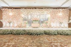 an elegant wedding setup with flowers and greenery at the head table in front of a floral backdrop