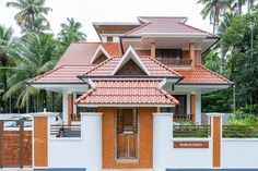 a white and brown house with red roof tiles on the front door, surrounded by palm trees