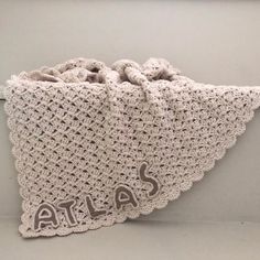 a white crocheted bag with the word atlas written on it