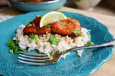 a blue plate topped with rice and meat covered in cilantro next to a fork