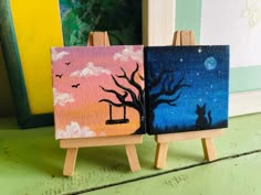 two paintings on easels sitting next to each other