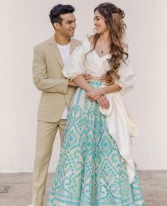 a man and woman standing next to each other in front of a white wall wearing formal clothing