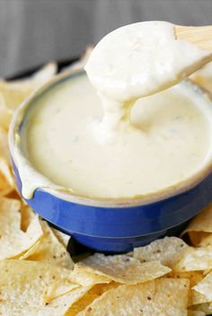 a blue bowl filled with white sauce and chips