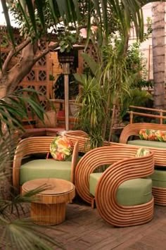 an outdoor seating area with wicker furniture and potted palm trees in the background