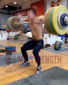 a shirtless man lifting a barbell in a gym