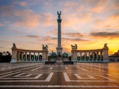 the sun is setting in front of a monument