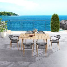 an outdoor table and chairs on a patio with the ocean in the backround