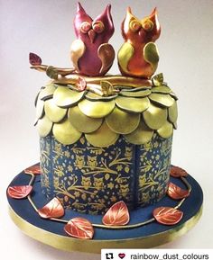 two cats sitting on top of a blue and gold cake